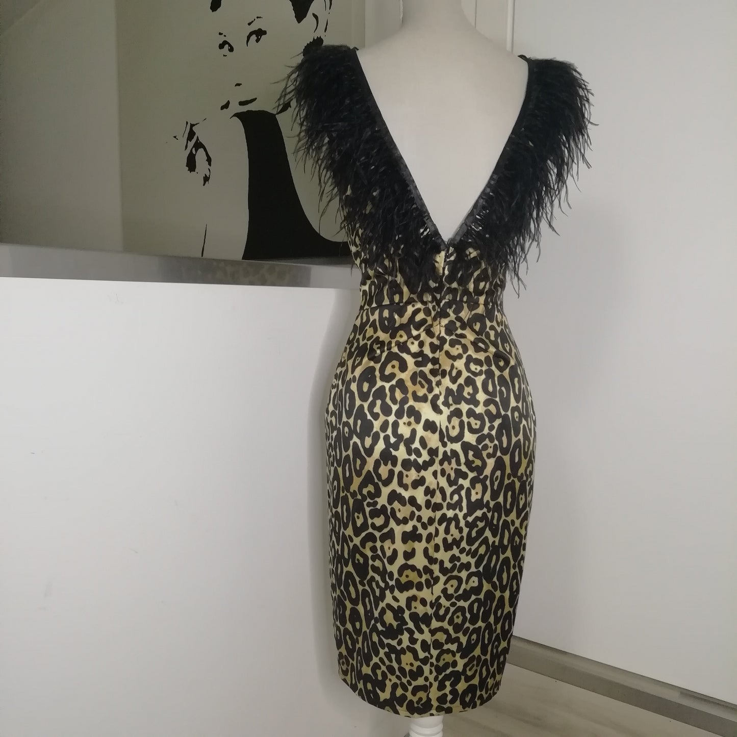 Abito ispirato ad uno stile anni 50. Scollo a barca sul davanti e scollatura profonda a punta sul dietro. Pence arrotondate davanti per dare maggiore slancio alla siluette e tagli dietri per dare risalto alla vita. Chiusura dietro con cerniera cucita a mano. La scollatura dell'intero abito è bordata con piume nere. La lunghezza dell'abito è al ginocchio (la si può fare personalizzata). L'abito è realizzato in tessuto misto cotone seta ( cotone 57% seta 43%)