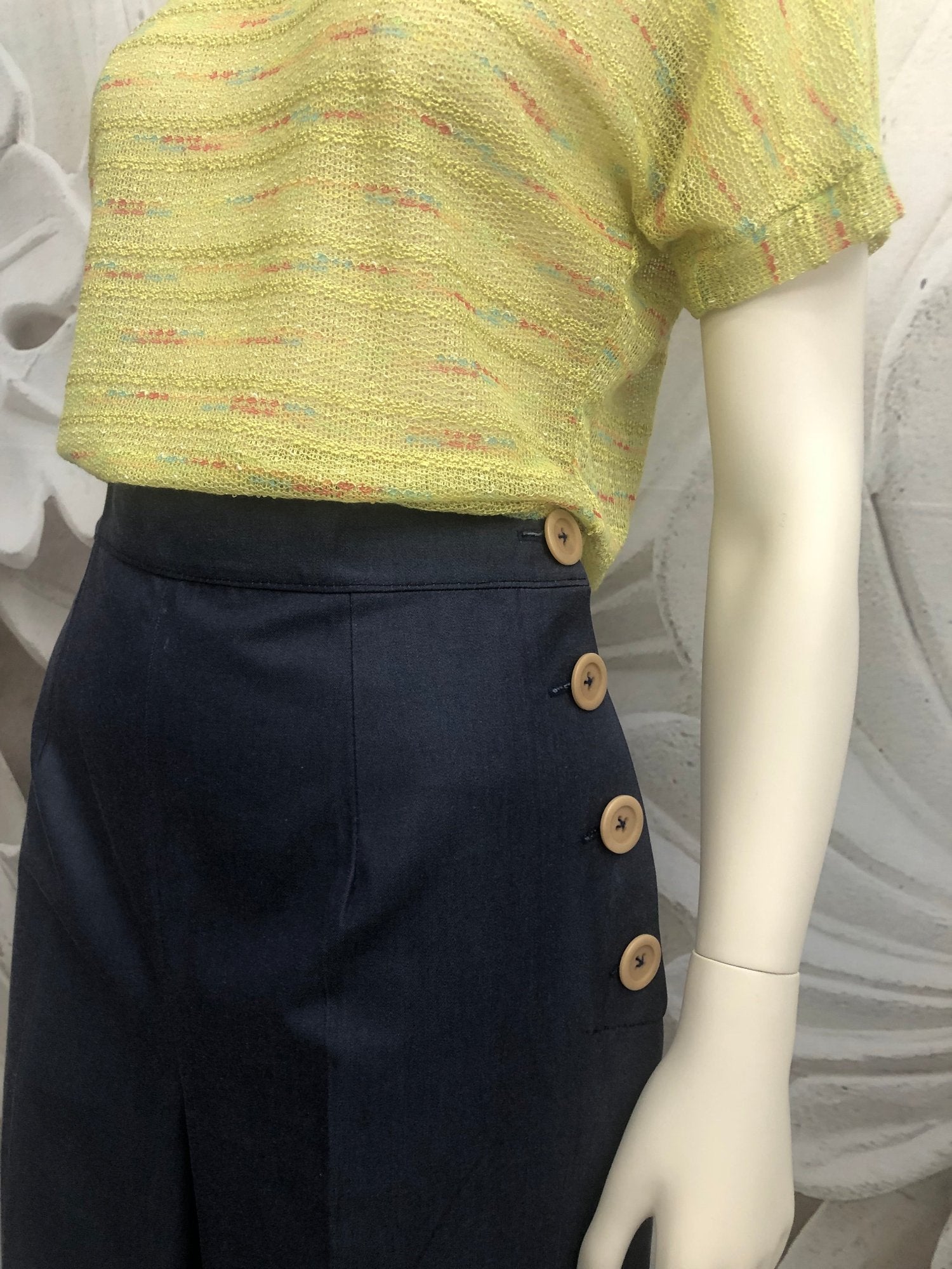 pantalone vita alta in gabardine blu allacciati con bottoni laterali beige. ts-hirt in maglia di cotone verde