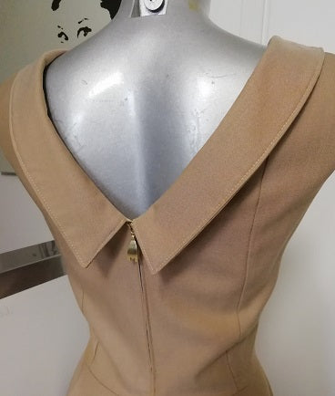 DETTAGLIO DELLO SCOLLO DIETRO DELL'ABITO IN STILE ANNI 50. SCOLLO A PUNTA BORDATO DA UN COLLETTO. CHIUSURA A ZIP IN METALLO DORATA CON MOTIVO A FORMA DI M